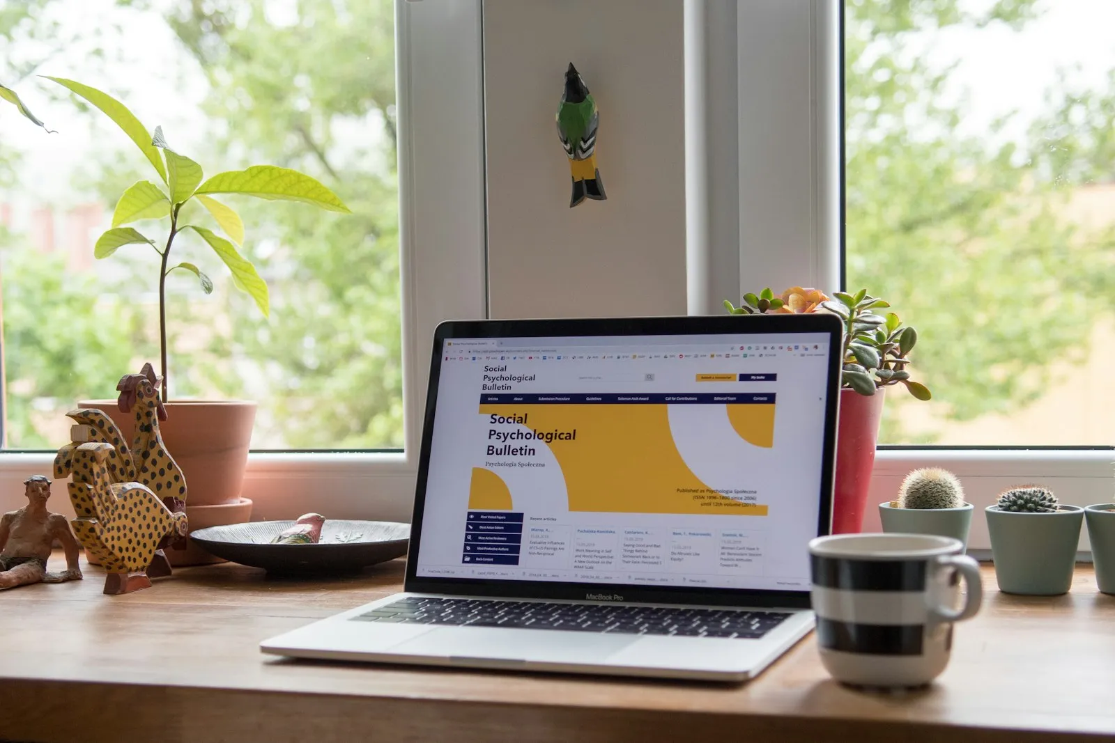 A home desk with a laptop and potted plants A home desk with a laptop and potted plants